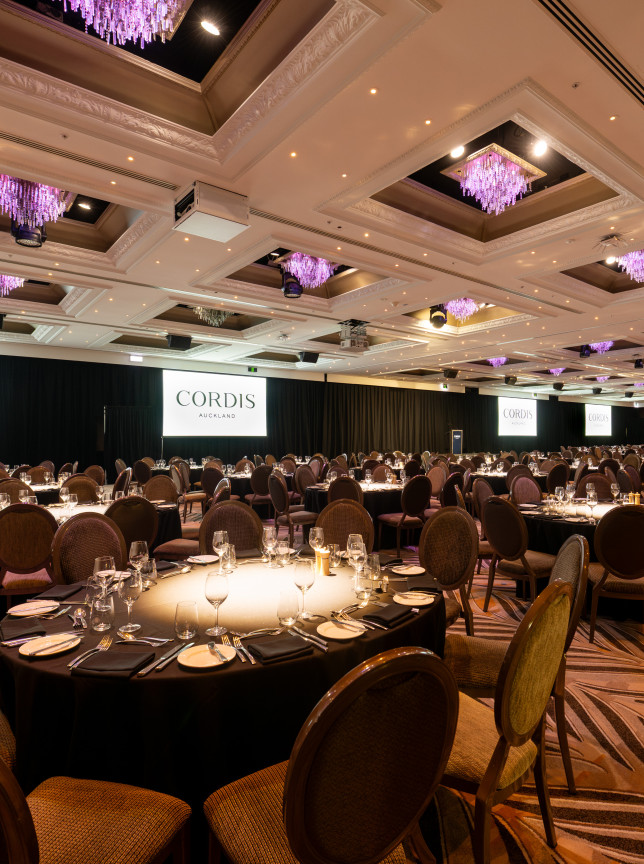 An elegant banquet setup in Cordis, Auckland's lavish ballroom, illuminated by crystal chandeliers.