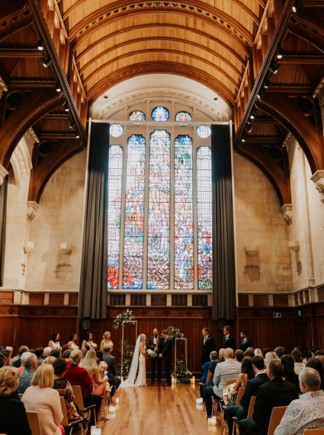 A wedding ceremony within the Gothic Revival Great Hall, Christchurch, showcasing its vaulted ceiling and stained glass.