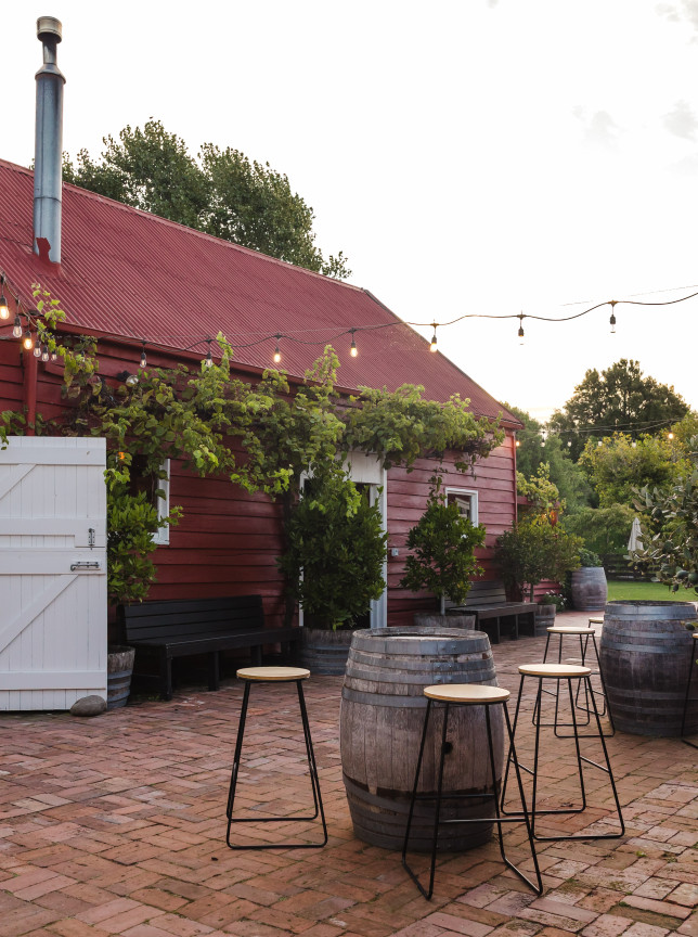 The rustic barn courtyard at Larcomb Vineyard, Christchurch, is set for an outdoor gathering under string lights.
