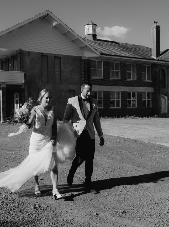 Newlyweds walk outside the historic brick lodge at LaValla Estate, a charming country venue near Auckland.