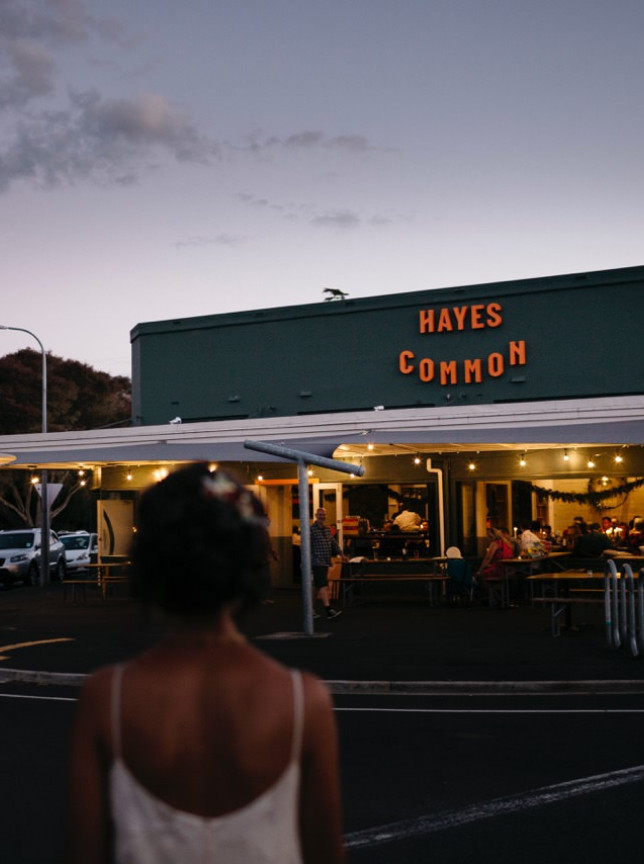 A couple approaches the vibrant outdoor dining area of Hayes Common, a relaxed mid-century-inspired eatery in Hamilton.