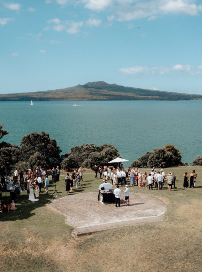 Guests at an outdoor event at the historic Officers Mess, Auckland, enjoying clifftop views of the Hauraki Gulf and Rangitoto Island.