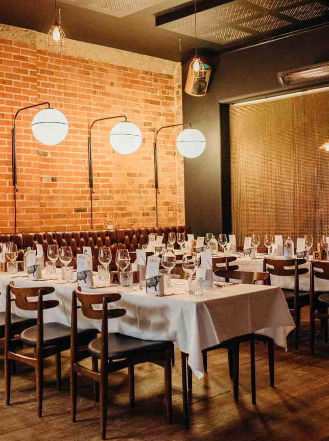 Vault 21 Dunedin's chic dining space features exposed brick walls and elegant table settings.
