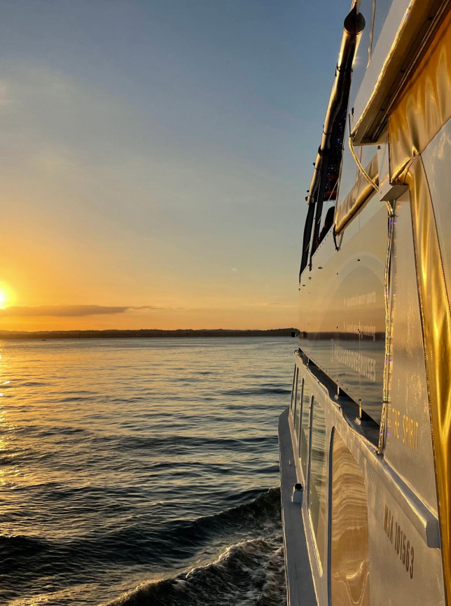 Ocean Groove Cruises' contemporary private charter boat glides through Auckland Harbour at sunset.