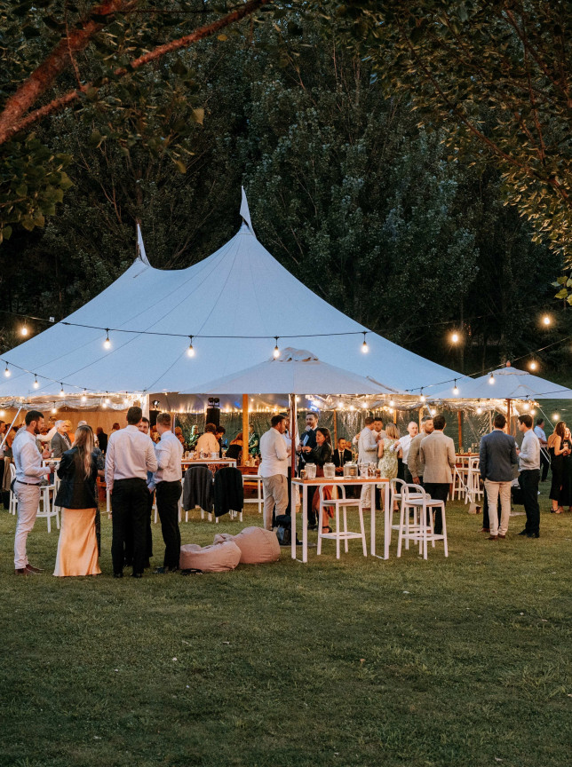 An elegant outdoor gathering under a string-lit marquee at The River House, a beautiful Hawke's Bay venue.