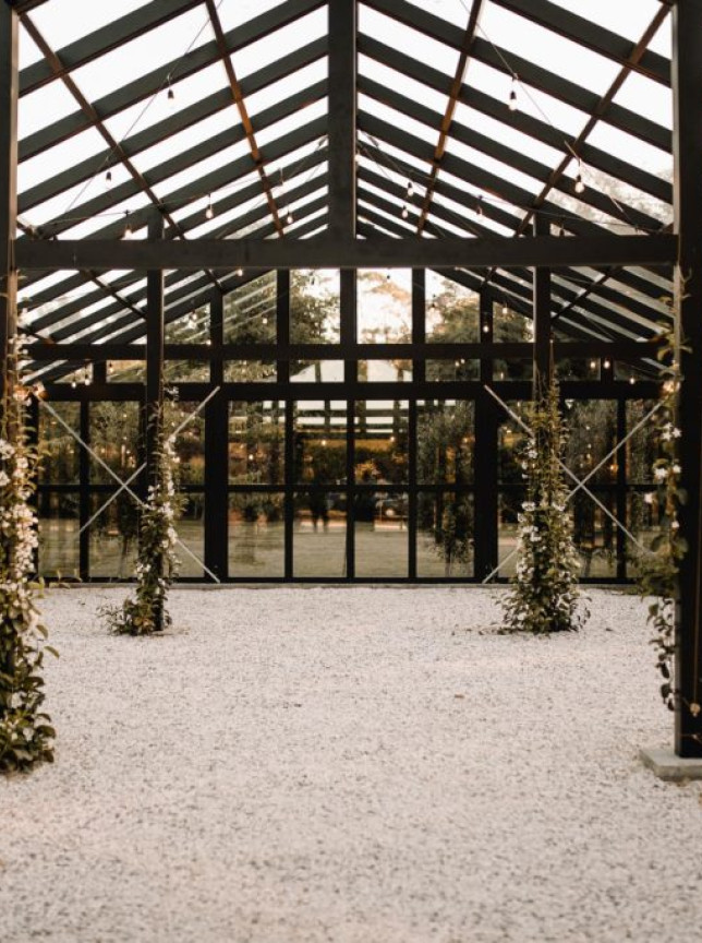 Black Walnut, Tauranga's chic glasshouse event space, features a gravel floor and pillars wrapped in white florals.