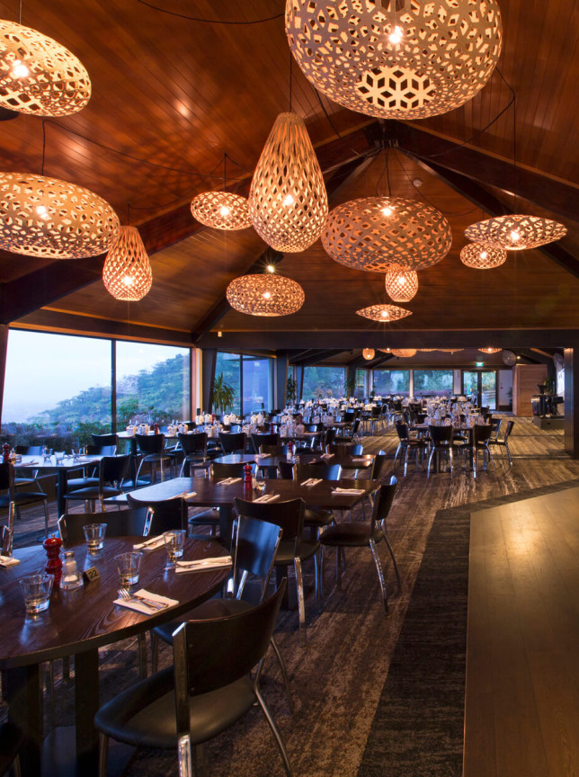 The contemporary timber-lined dining room at Stratosfare Restaurant & Bar in Rotorua features distinctive David Trubridge lights and panoramic views.