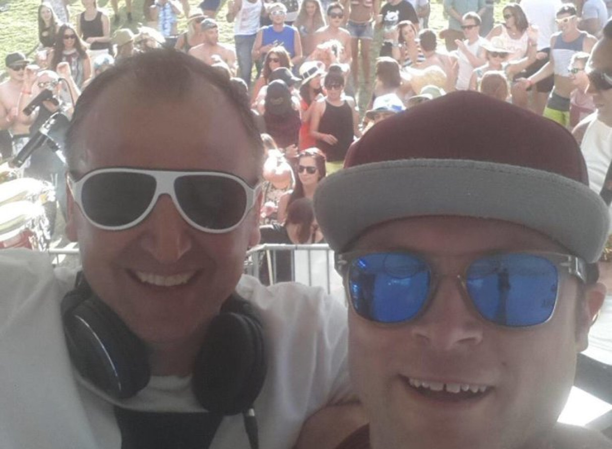 An outdoor festival scene with DJ Grant Marshall, known for his party house style, smiling with a guest in Auckland.