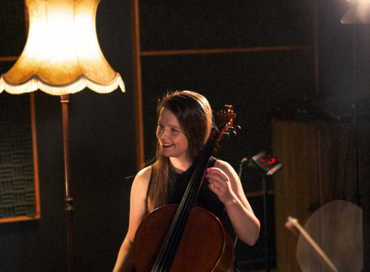 A cellist from Auckland's sophisticated The Black Quartet performs, illuminated by a warm lamp.