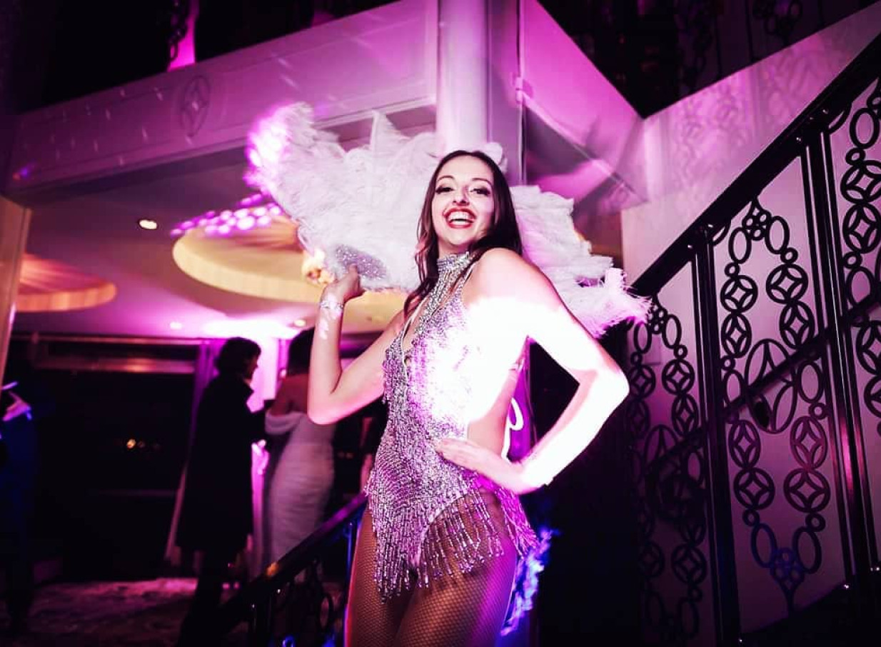 Finesse Entertainment provides a vibrant showgirl performance in a sparkling, feathered costume at an Auckland event.
