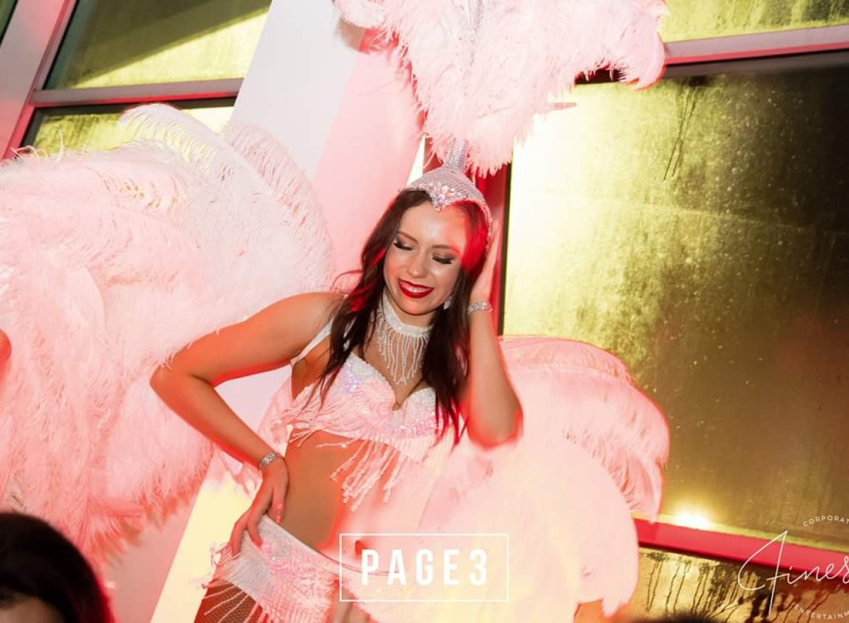 Finesse Entertainment Auckland features a glamorous performer in a sparkling white costume with feathered headpiece and wings.