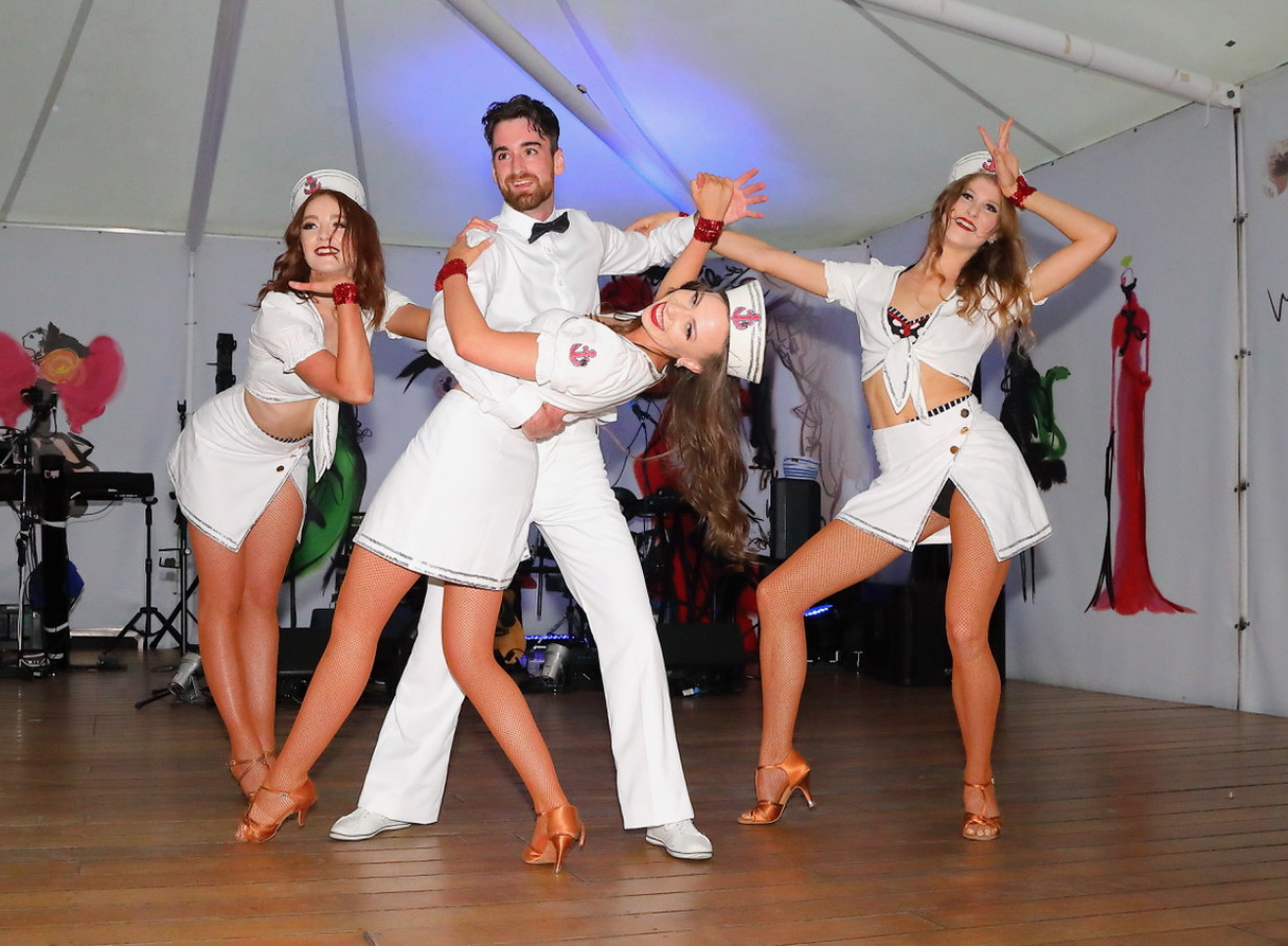 Finesse Entertainment dancers deliver an energetic themed performance on a wooden stage in Auckland.