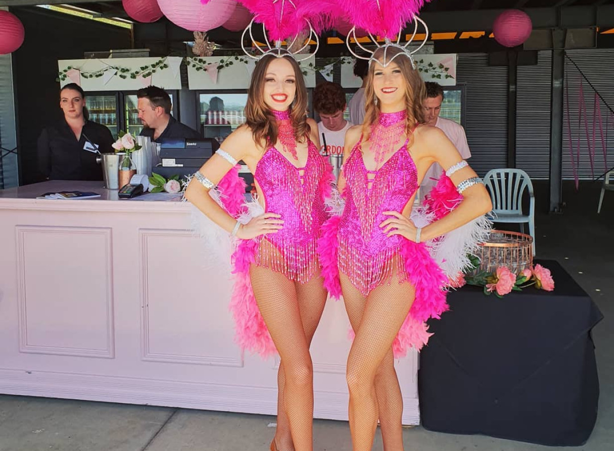 Dazzling showgirl performers from Finesse Entertainment Auckland enchant guests with vibrant pink costumes.