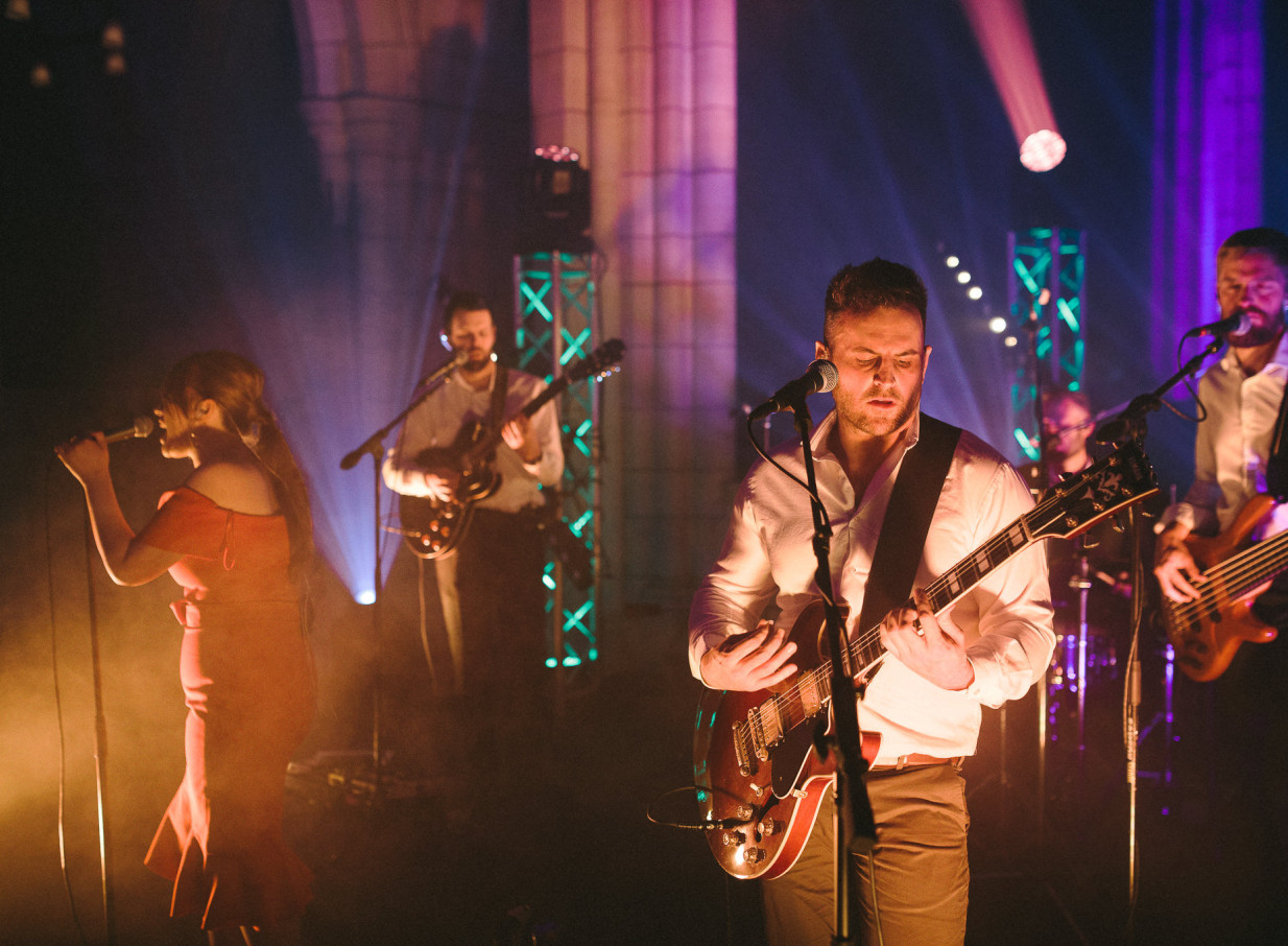 Auckland Bands captivates an Auckland event audience with a dynamic live performance in a grand, dramatically lit hall.