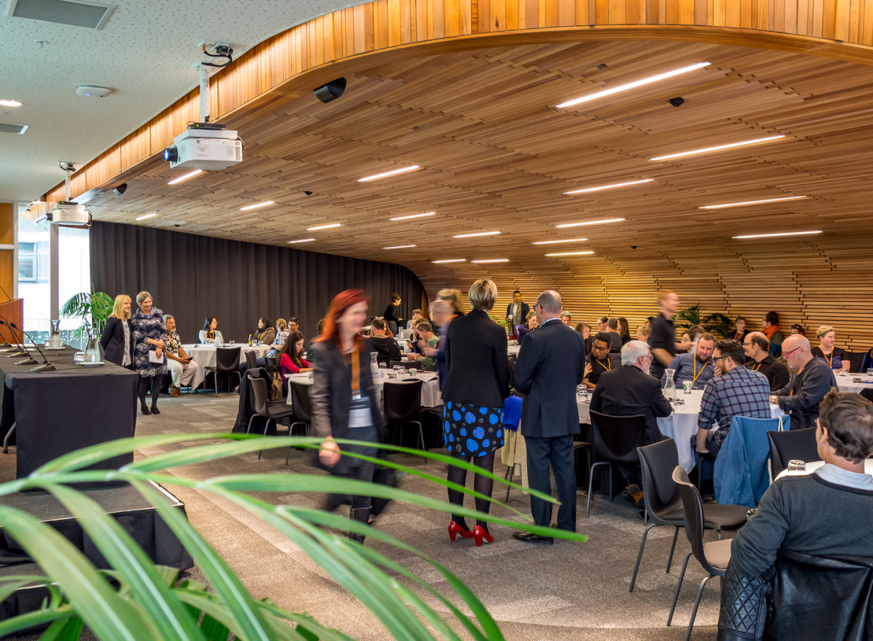 A modern conference space at Auckland City AUT Events + Venues, featuring a spacious room with a distinctive curved wooden ceiling.