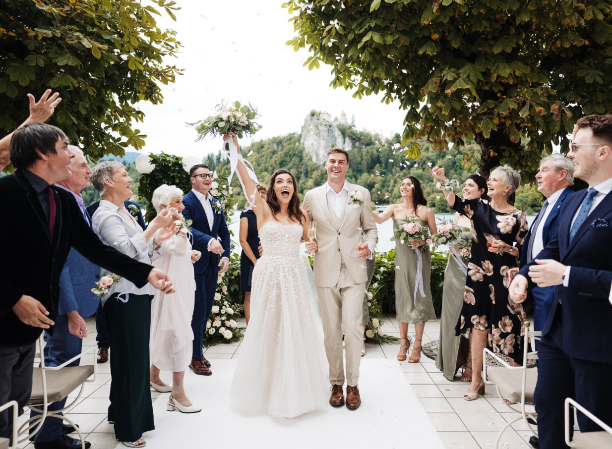 Auckland-based wedding photographer Zahn captures a joyful outdoor recessional with confetti at a European-inspired castle and lake venue.