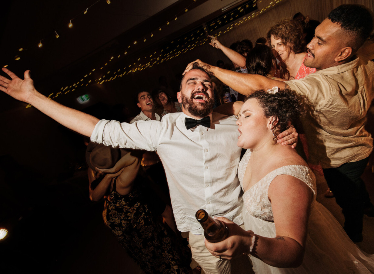 Auckland photographer Zahn captures an unscripted, joyful moment of guests enthusiastically dancing at a wedding reception.