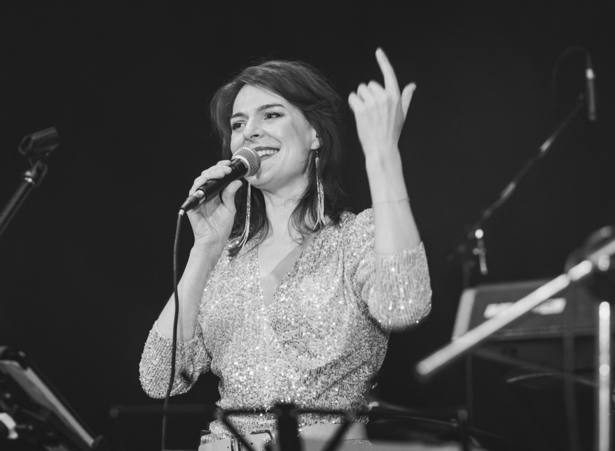 The Hustle's smiling vocalist, in a dazzling top, delivers a high-energy performance in Auckland.