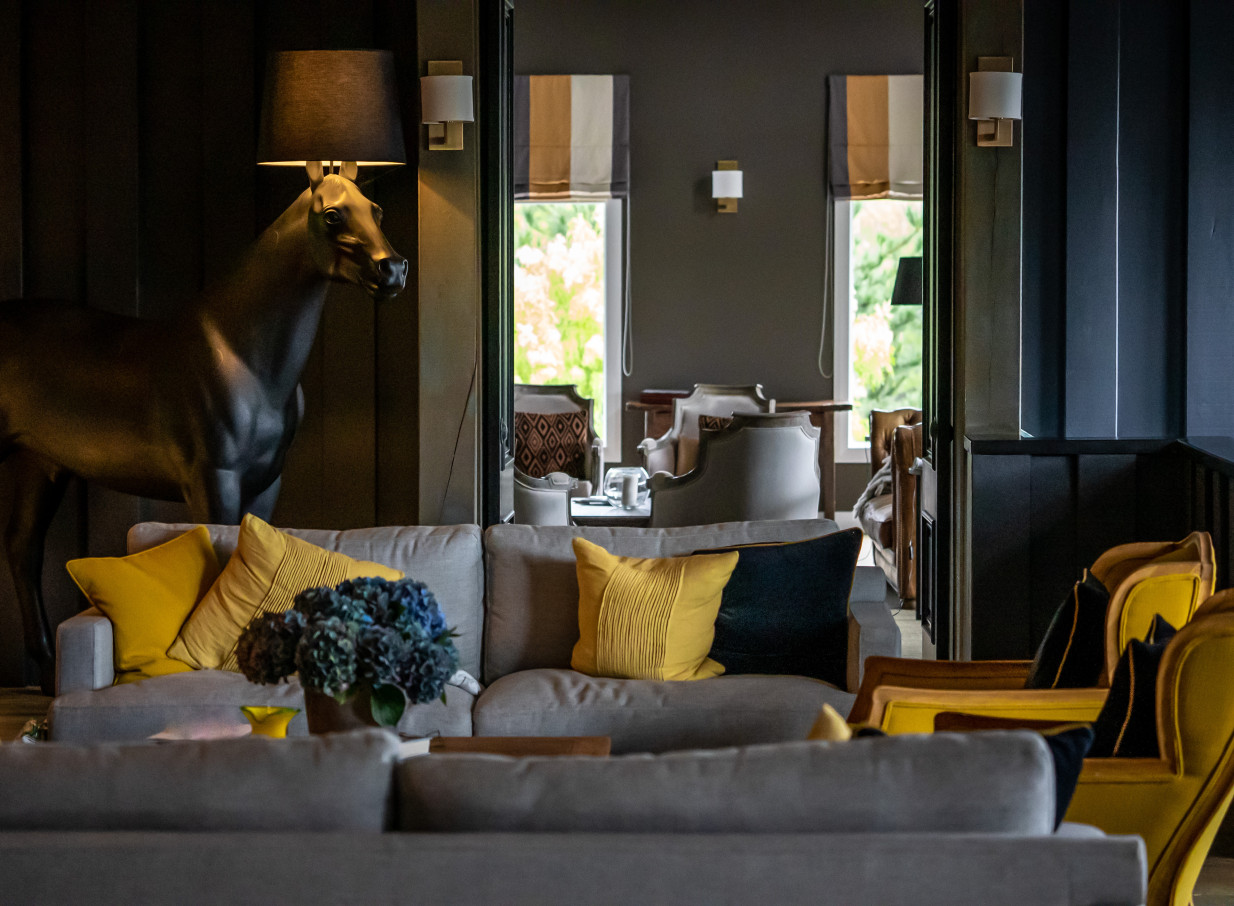 A stylish lodge lounge at Woodhouse Mountain Lodge, Auckland, featuring modern furnishings and a distinctive horse lamp.