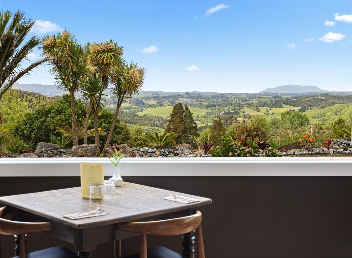A dining area with panoramic views of rolling hills at the contemporary Woodhouse Mountain Lodge in Auckland.