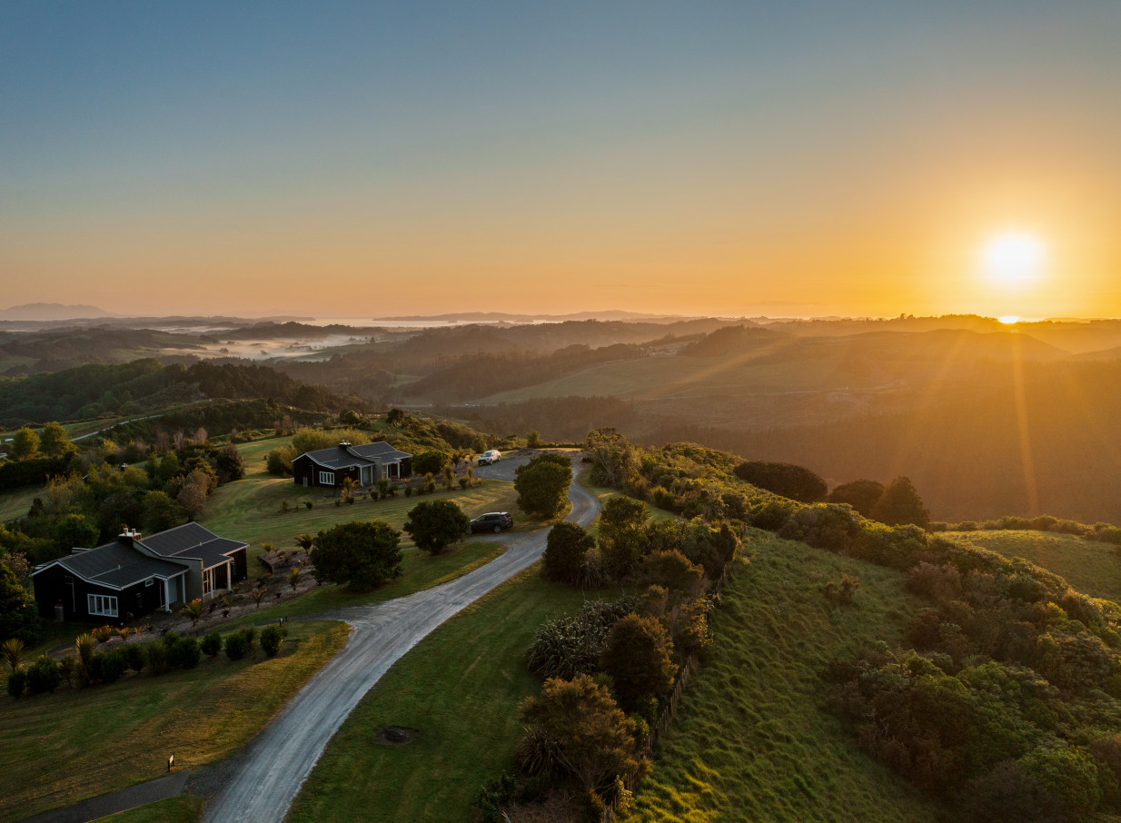 Contemporary villas at Woodhouse Mountain Lodge, Auckland, overlook a stunning misty mountain sunrise.