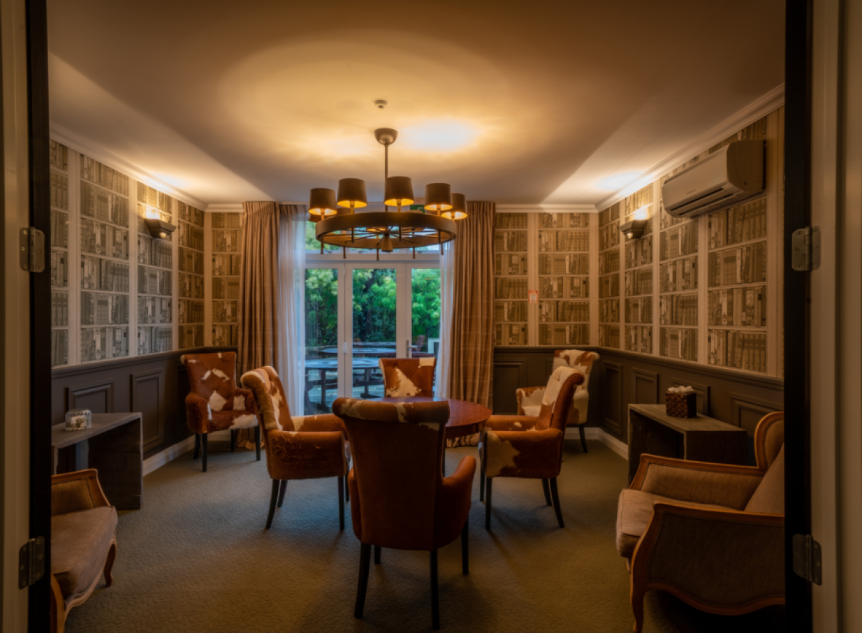A private, lodge-style lounge at Woodhouse Mountain Lodge in Auckland features library wallpaper and plush seating.