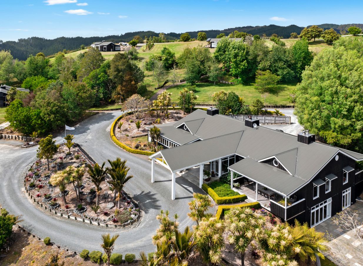 Aerial view of Woodhouse Mountain Lodge, Auckland, showcasing its contemporary lodge architecture amidst rolling green hills.