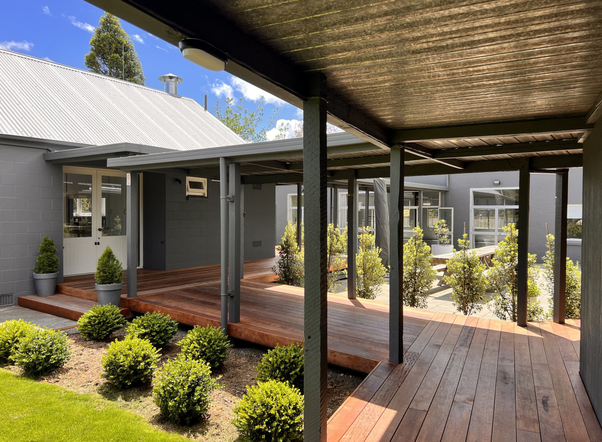 A covered wooden deck area with lush greenery at Omatua, a modern country lodge venue in Hawke's Bay.