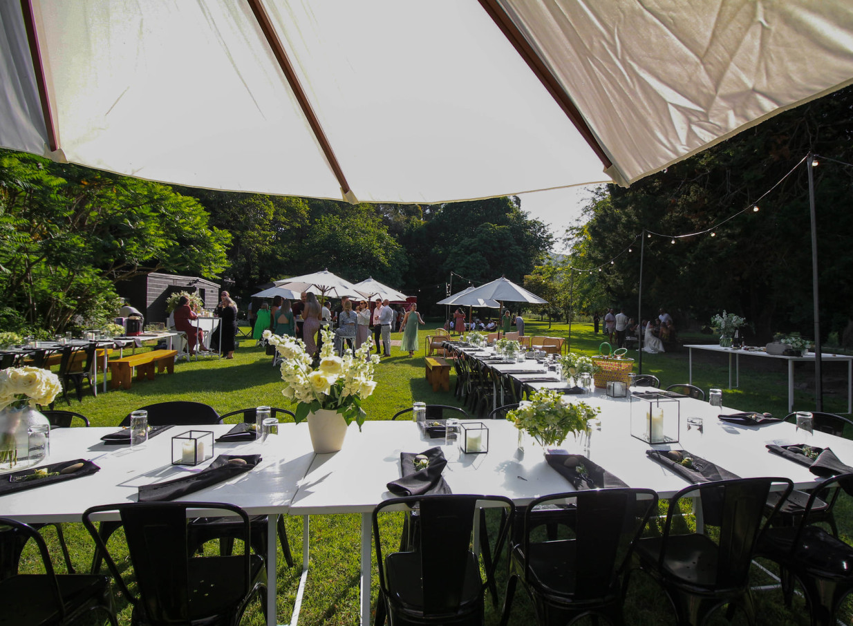 An outdoor dining event unfolds within the picturesque garden setting of Omatua, a rural riverside lodge in Hawke's Bay.