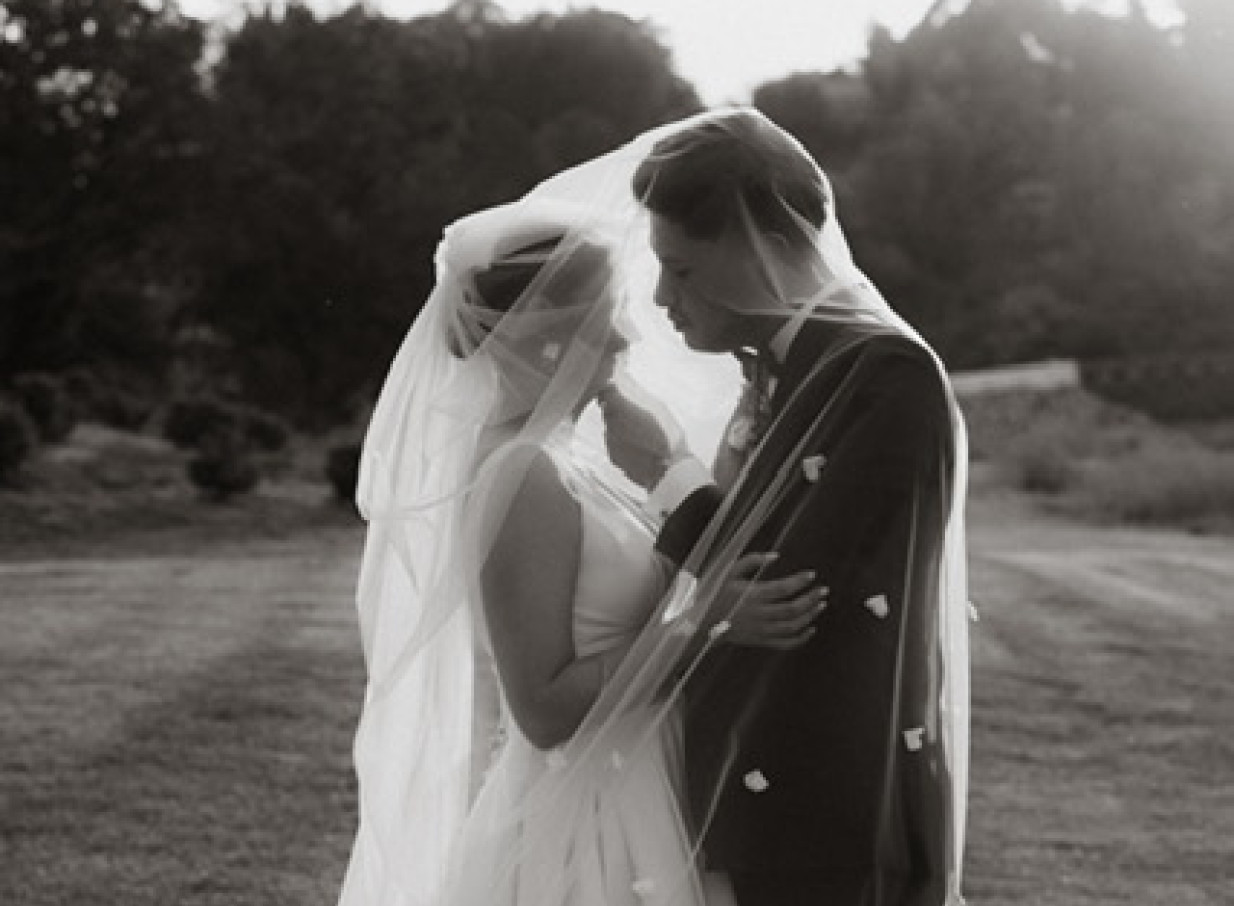 A newlywed couple shares a tender moment under a veil during their outdoor ceremony at the Omatua Riverside Lodge in Hawke's Bay.