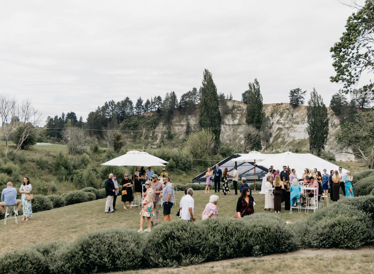 Guests mingle on Omatua's expansive rural lawns, a picturesque Hawke's Bay venue, featuring white event marquees.
