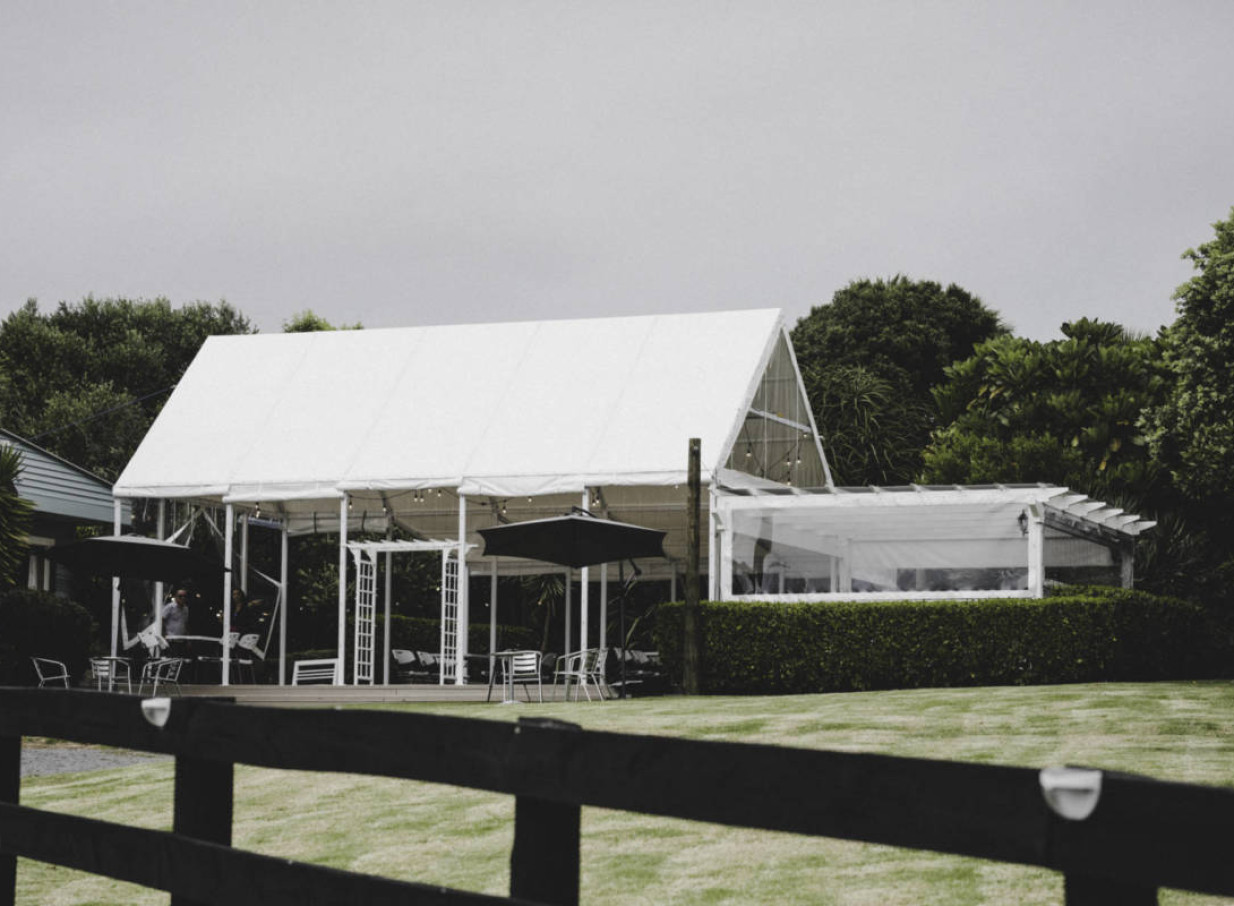 An elegant white marquee provides a covered event space at Connemara Country Lodge, a country venue in Auckland.