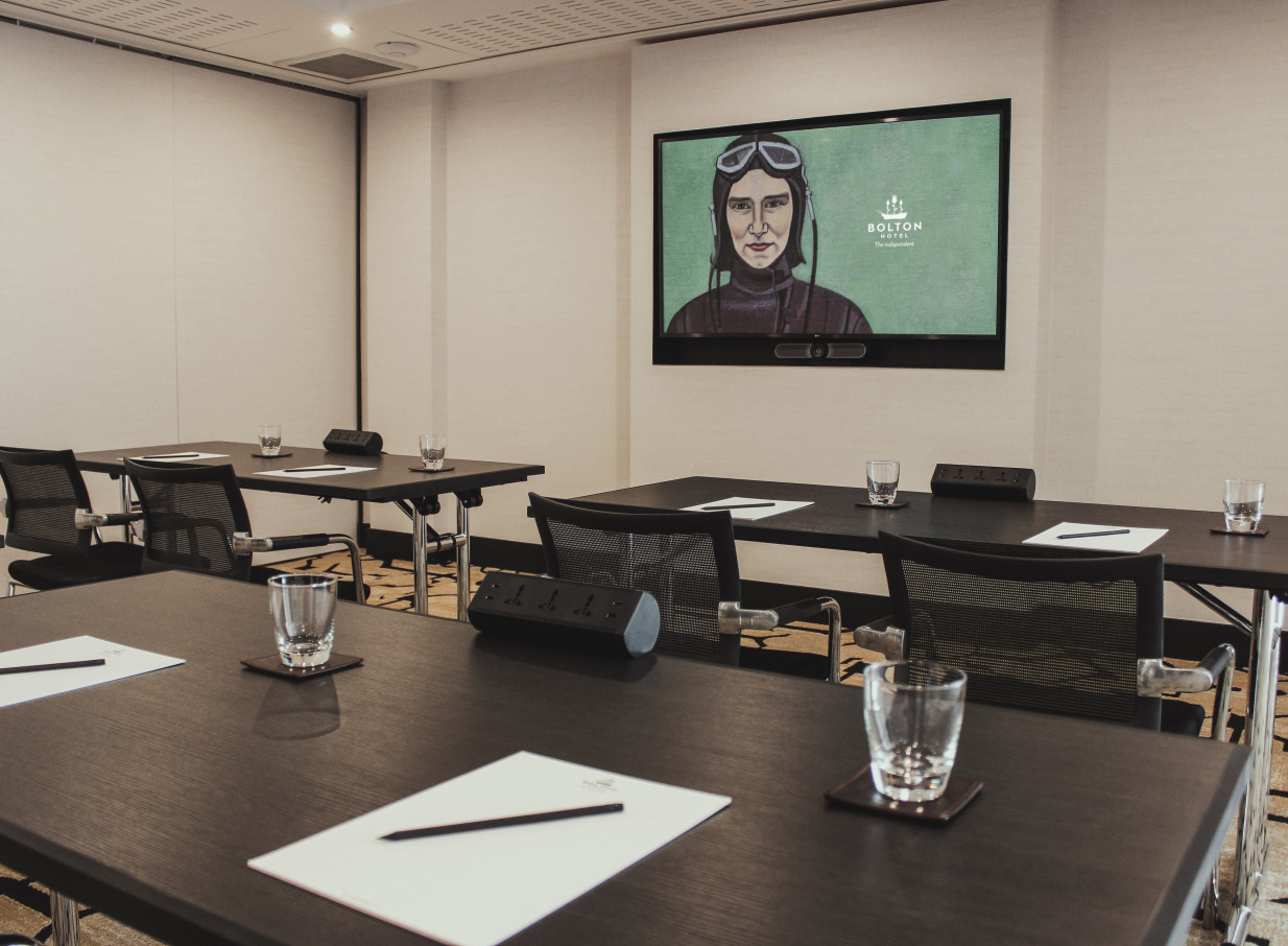 An elegant and high-tech meeting room at the boutique Bolton Hotel in Wellington, featuring dark tables and a large presentation screen.
