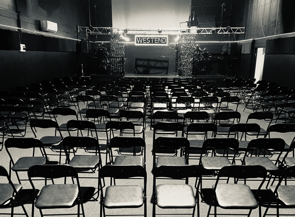 Westend, Christchurch, presents a modern, flexible indoor event space with rows of chairs facing a neon-signed stage.