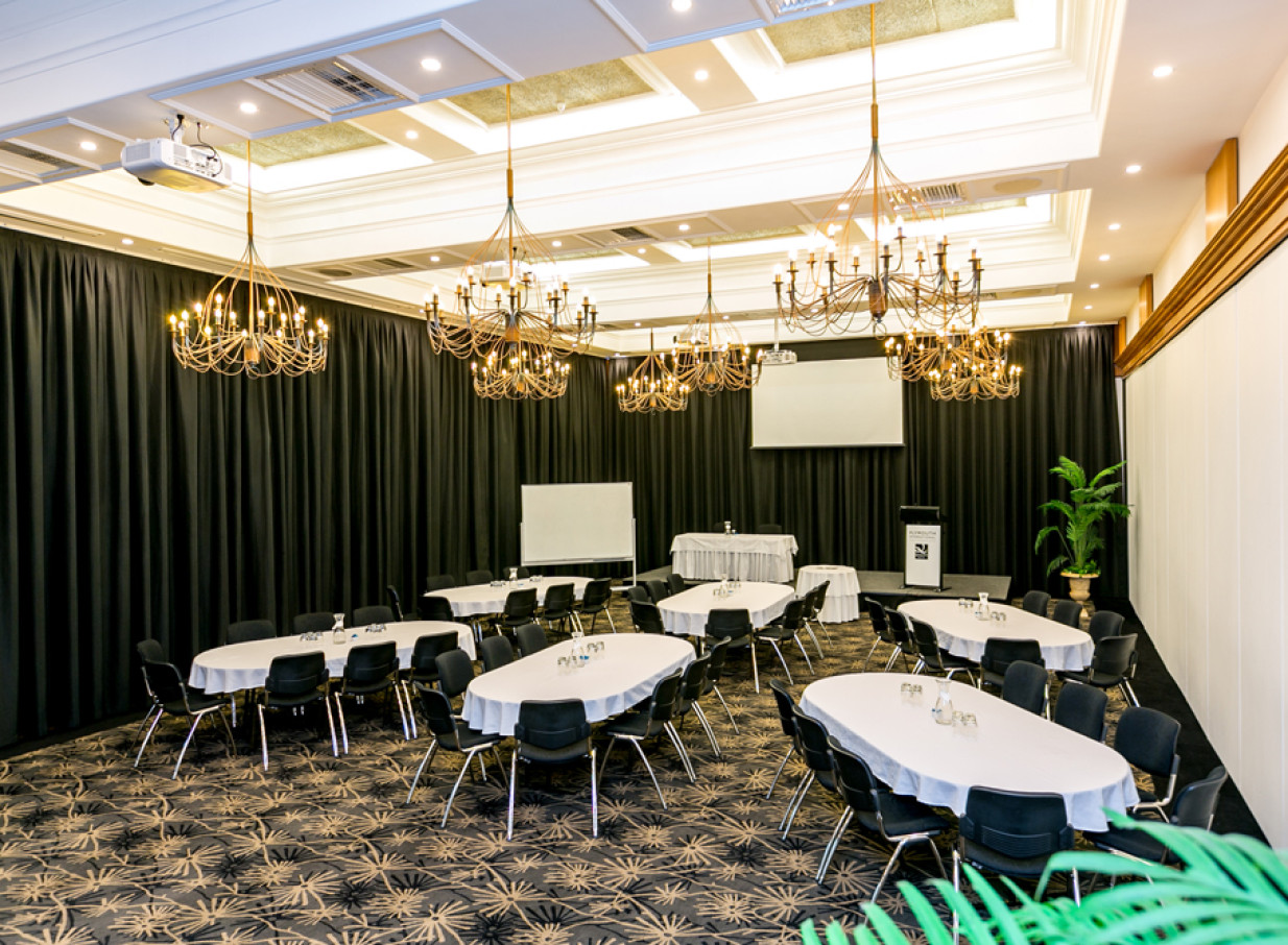 The elegant conference room at Plymouth International in New Plymouth features modern furnishings and chandeliers, ready for any event.