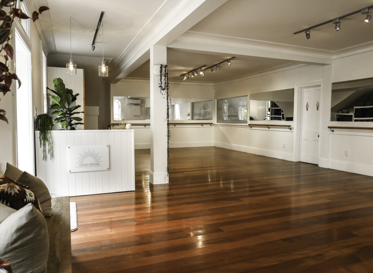 The main yoga studio and reception area at Auckland's Yoga House showcases heritage character with polished wood floors and high ceilings.
