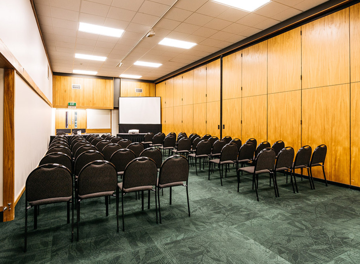 A modern conference room with wood-paneled walls and rows of chairs at Palmy Conference + Function Centre, Palmerston North.