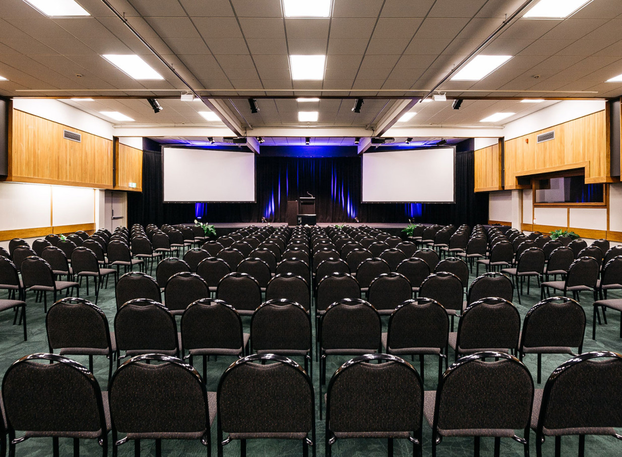 A modern, purpose-built theatre-style conference room at Palmy Conference + Function Centre, Palmerston North, with dual screens.