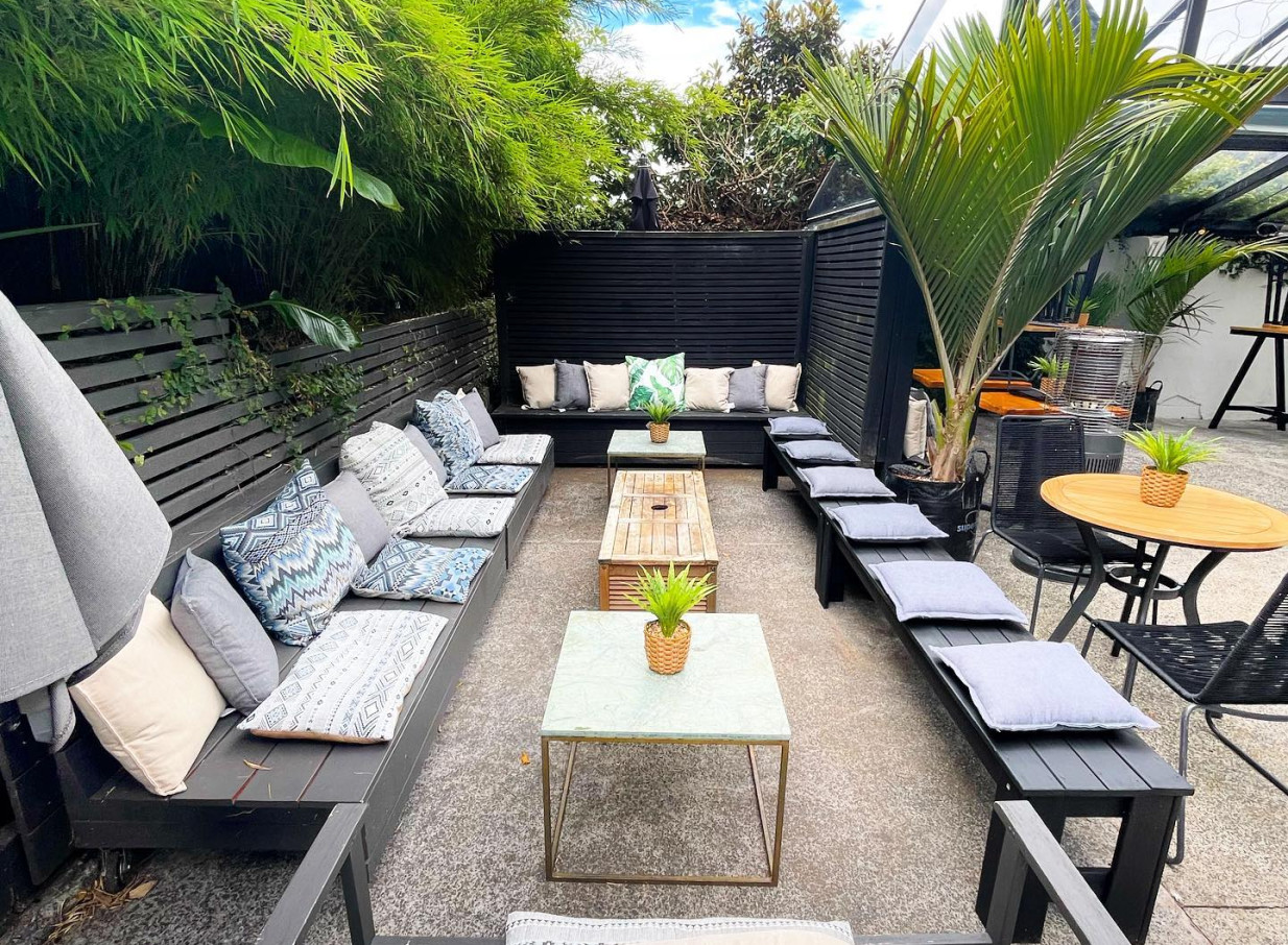 An inviting outdoor seating area with lush greenery and comfortable benches at Rosanna's urban oasis in Auckland.