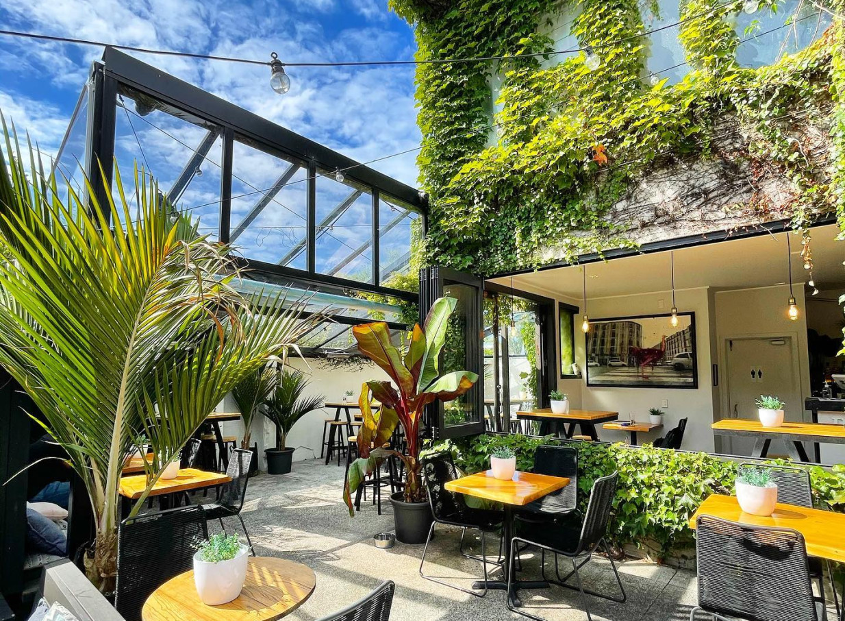 Rosanna's, Auckland, features a lush, tropical-inspired outdoor conservatory with inviting seating.