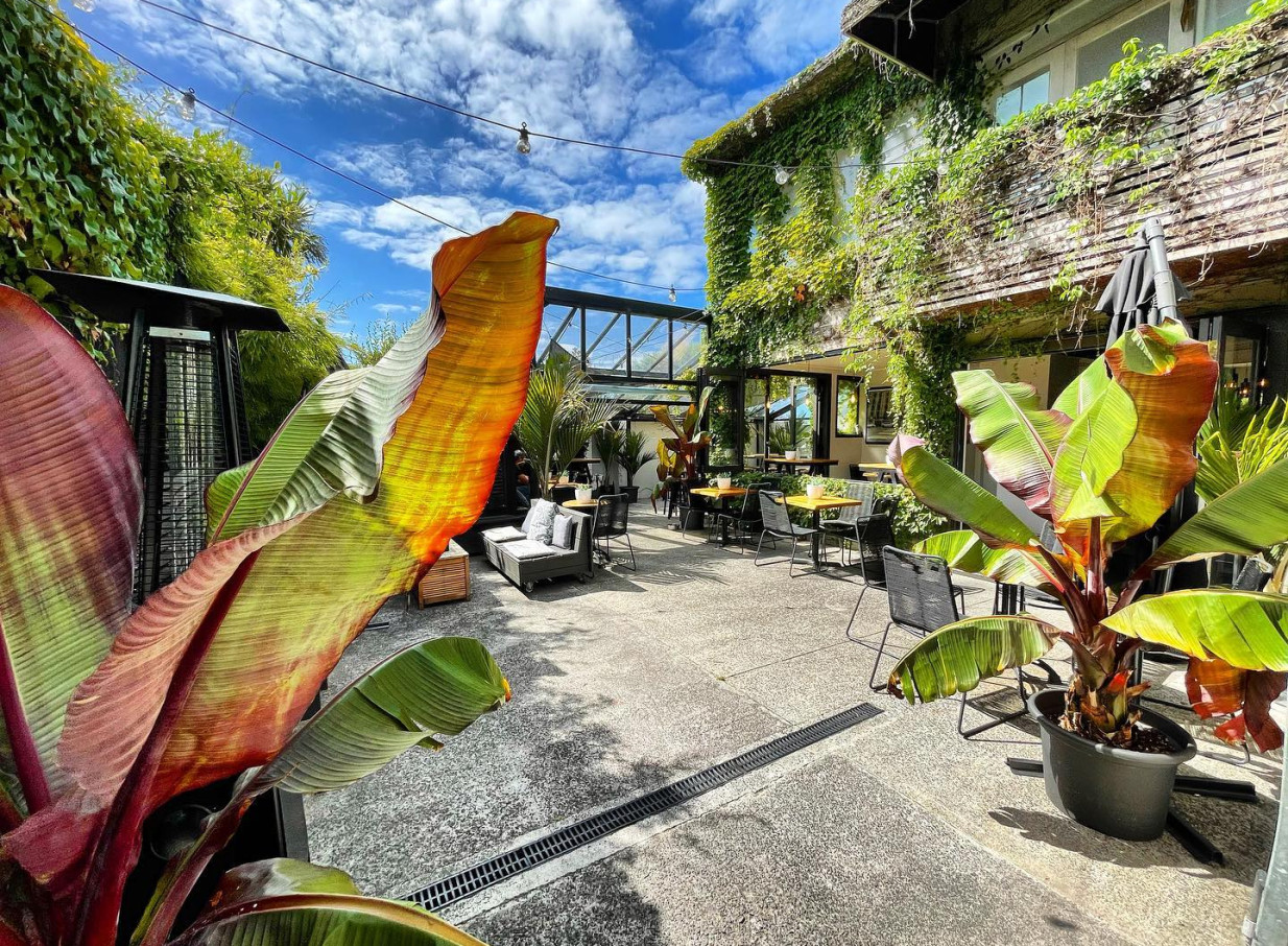 A lush, Bali-inspired outdoor dining courtyard with tropical plants and seating at Rosanna's Garden Bar in Auckland.