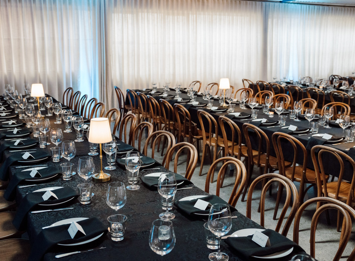 A formal dining setup with black settings and bentwood chairs at Wellington's industrial-chic Whisky & Wood venue.