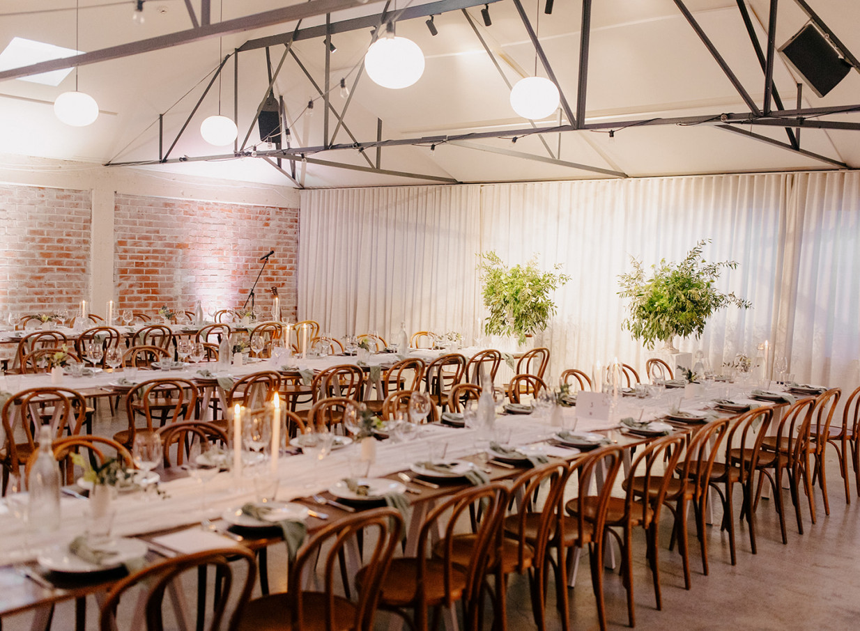 An industrial-chic dining room with long tables and bentwood chairs is elegantly set at Whisky & Wood in Wellington.