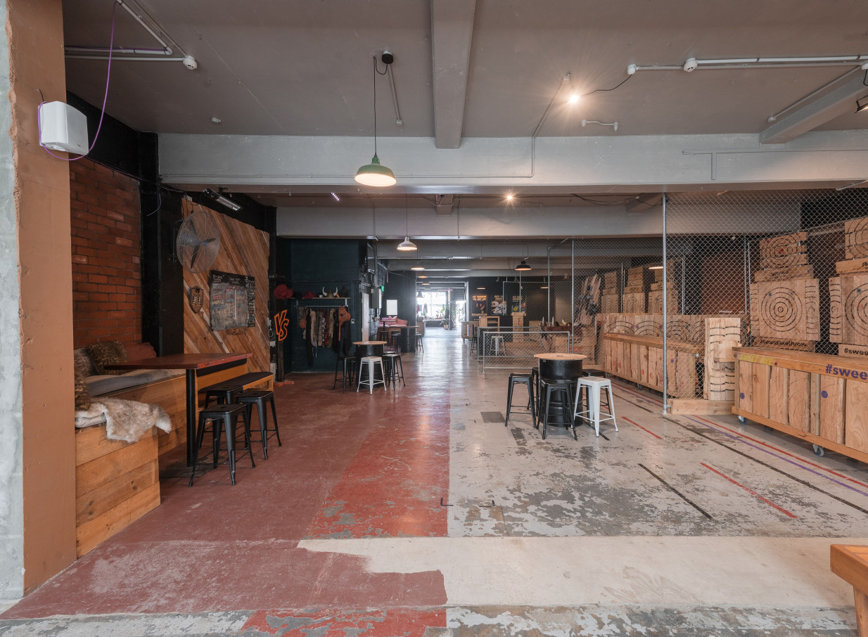 An industrial-chic axe-throwing area at Whisky & Wood in Wellington, featuring exposed brick and wooden targets.