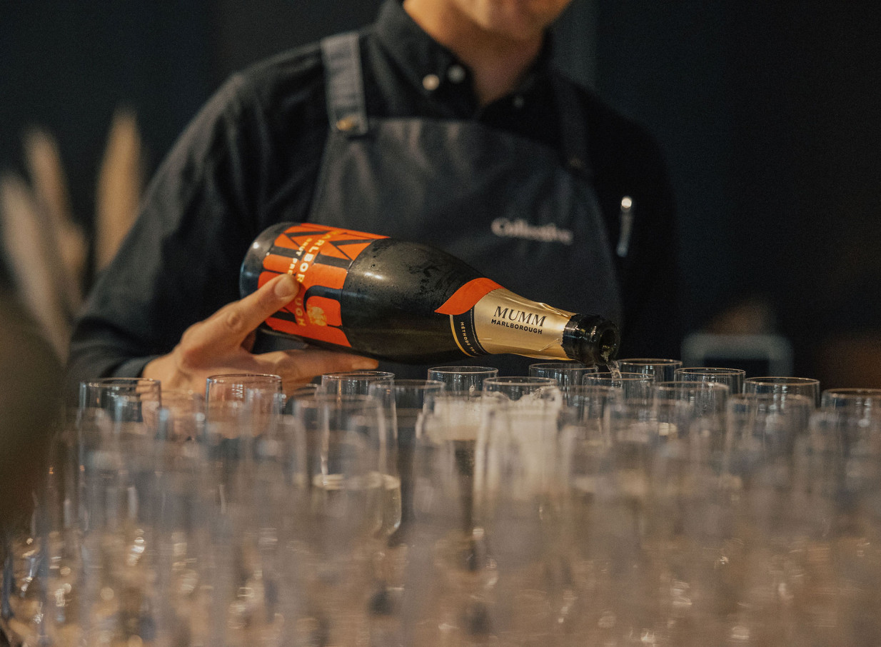 A server provides elegant champagne service at Orakei Bay, Auckland's sophisticated waterside event venue.