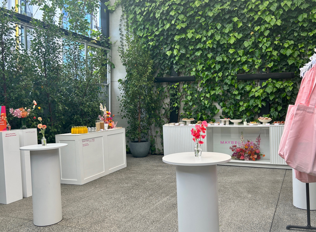 An industrial-style courtyard event at Space On Crummer, Auckland, featuring catering bars and lush green walls.