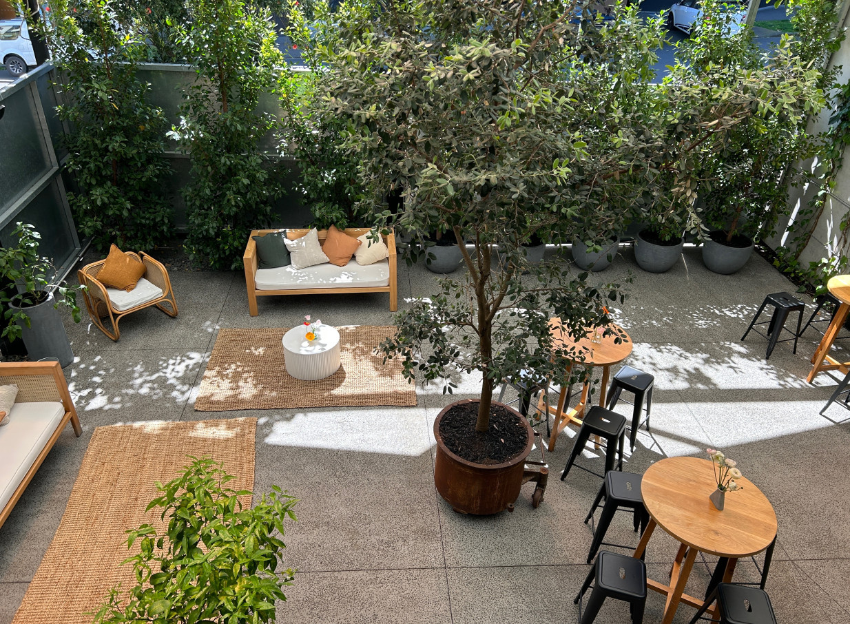 A contemporary outdoor seating area in the industrial-chic, leafy green courtyard at Space On Crummer, Auckland.
