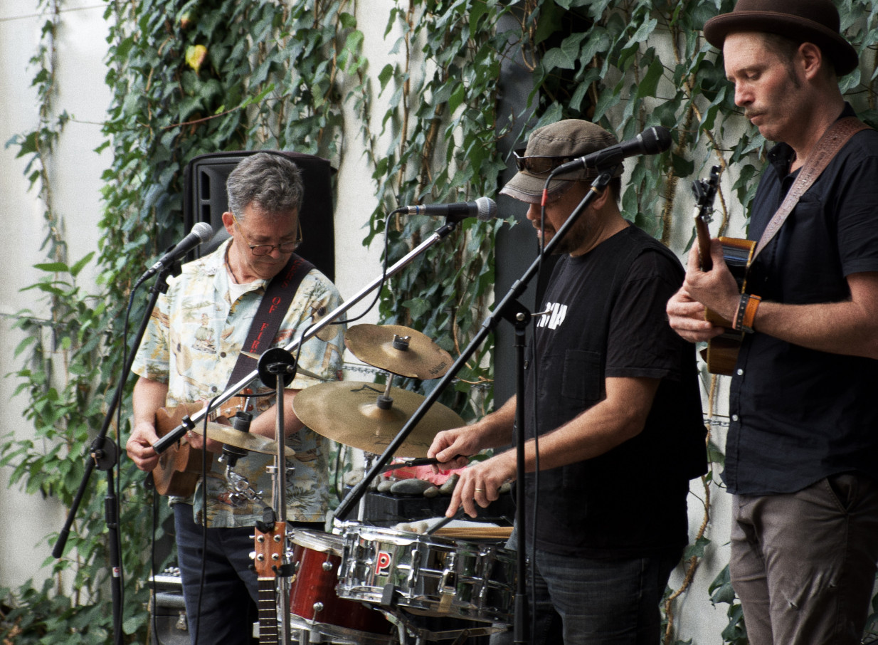 A band performs in Space On Crummer's industrial-chic Auckland courtyard, set against a leafy green wall.