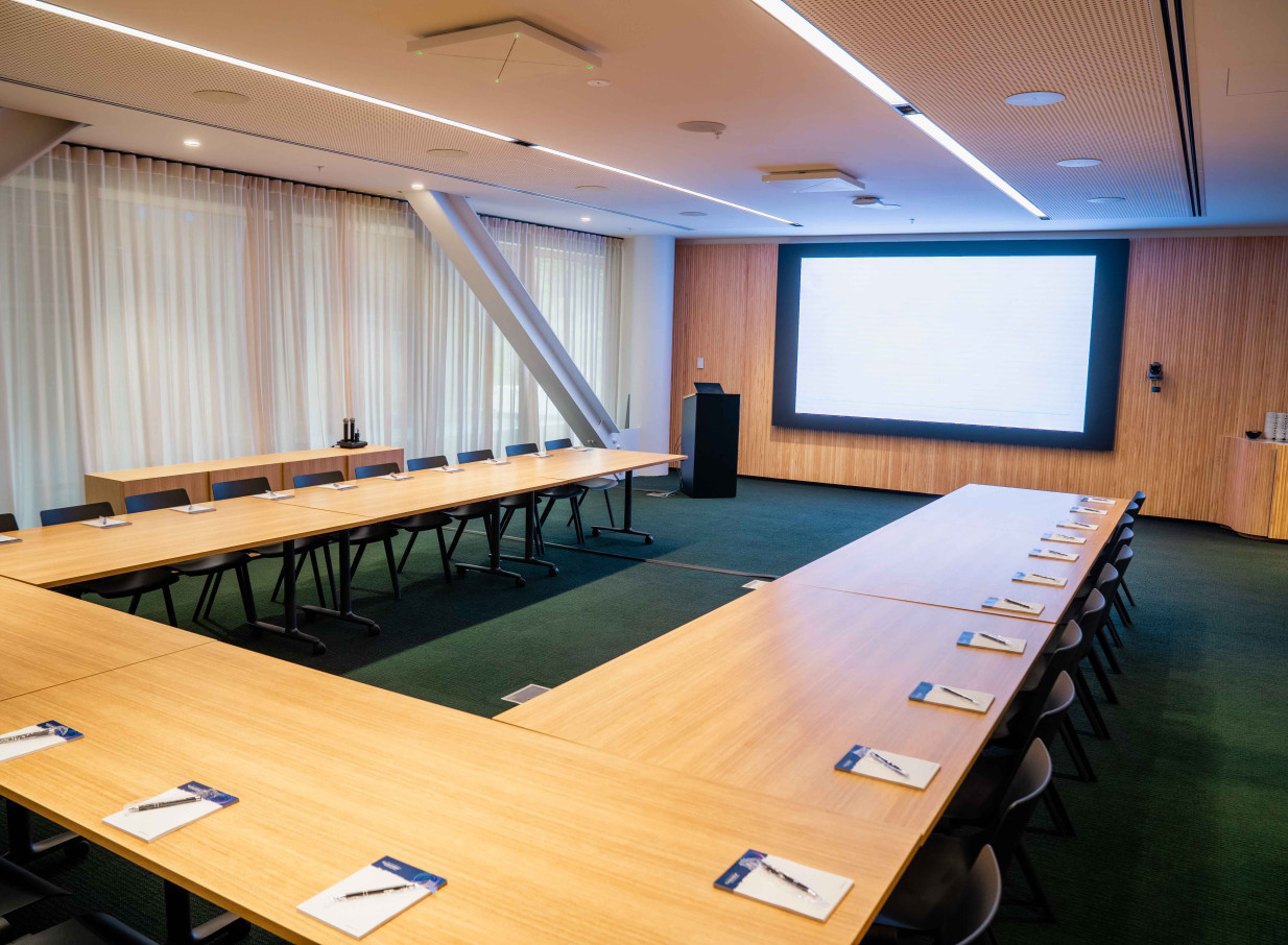 A modern conference room with U-shaped tables and a large projection screen at Bowen Campus by Precinct Flex, Wellington.