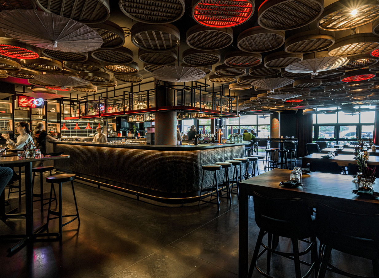 QT Wellington's Hot Sauce bar in Wellington features a vibrant, Asian-inspired dining area with unique dumpling steamer ceiling lights.